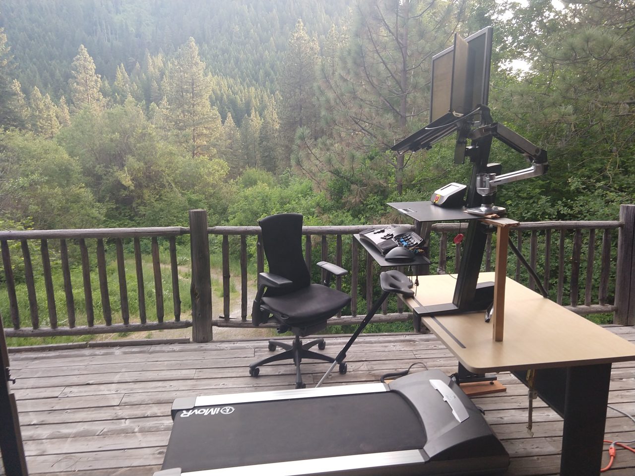 treadmill computer desk on deck, trees in background