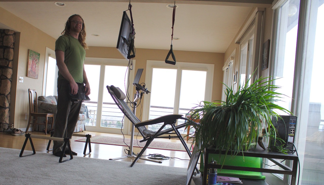 photo of standing with a monitor suspended by rope, keyboard suspended from pants